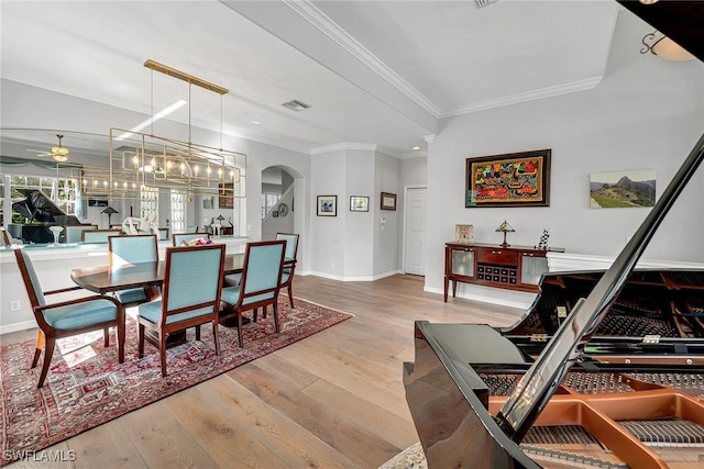 dining space with arched walkways, crown molding, a ceiling fan, wood finished floors, and baseboards