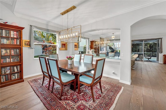 dining space with baseboards, arched walkways, hardwood / wood-style floors, and ornamental molding