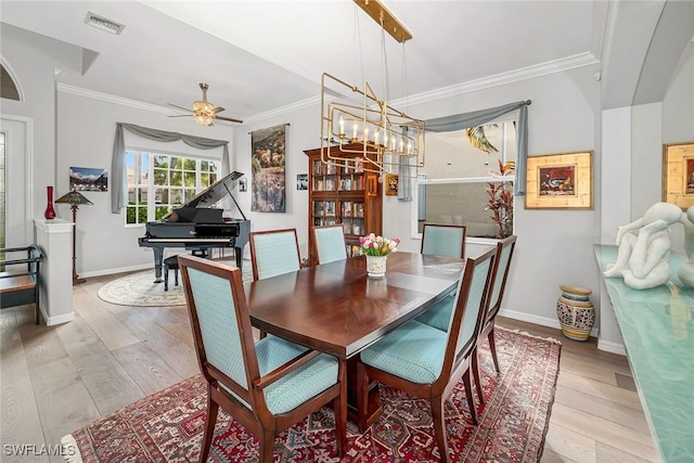 dining area with baseboards, light wood finished floors, visible vents, and crown molding