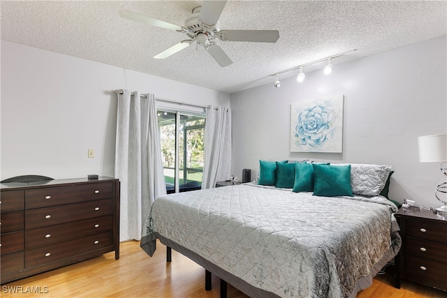 bedroom with access to exterior, light wood-style flooring, ceiling fan, a textured ceiling, and track lighting