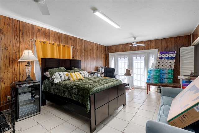 bedroom with light tile patterned floors, ceiling fan, access to outside, and wood walls