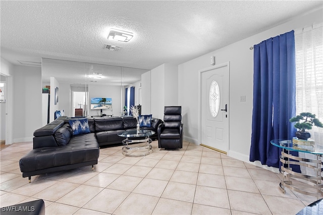 living area featuring visible vents, a textured ceiling, baseboards, and light tile patterned floors