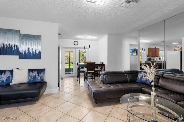 living room with a textured ceiling, light tile patterned flooring, visible vents, and a healthy amount of sunlight