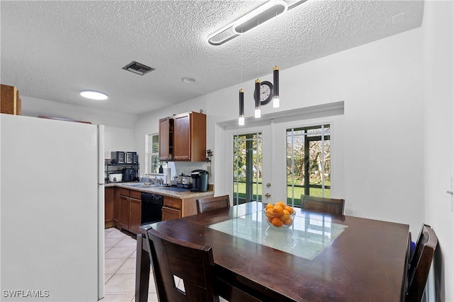 kitchen with light tile patterned floors, visible vents, hanging light fixtures, freestanding refrigerator, and dishwasher