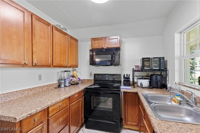 kitchen featuring black appliances, a textured ceiling, light countertops, and a sink