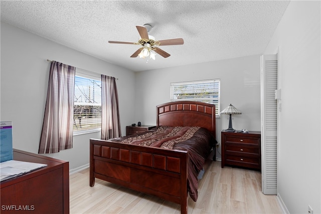 bedroom with light wood-type flooring, multiple windows, and a textured ceiling