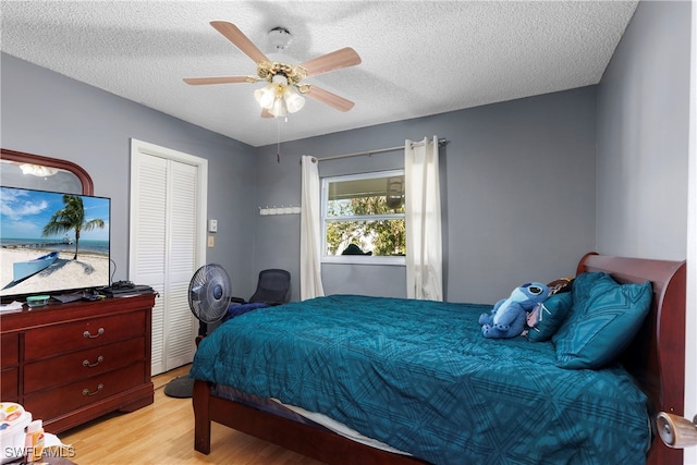 bedroom featuring a ceiling fan, a closet, a textured ceiling, and wood finished floors