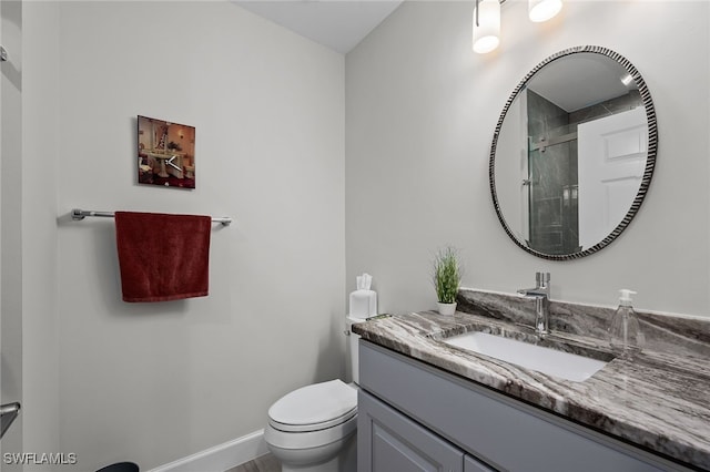 full bath featuring a stall shower, baseboards, vanity, and toilet