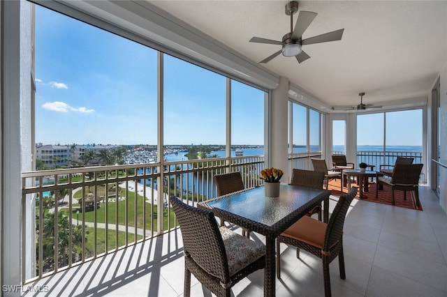 sunroom featuring a ceiling fan and a water view