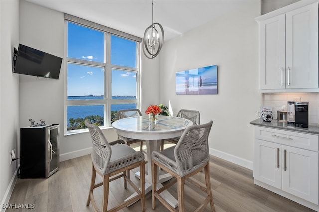 dining room featuring baseboards, an inviting chandelier, and light wood-style floors