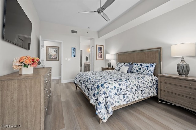 bedroom featuring connected bathroom, wood finished floors, visible vents, and baseboards