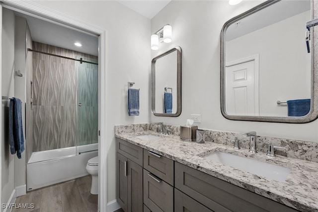 full bathroom with toilet, enclosed tub / shower combo, a sink, and wood finished floors