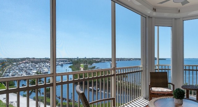 sunroom with ceiling fan and a water view