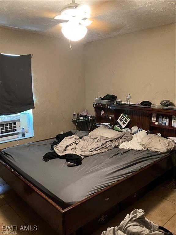 bedroom featuring cooling unit, a textured ceiling, and tile patterned floors