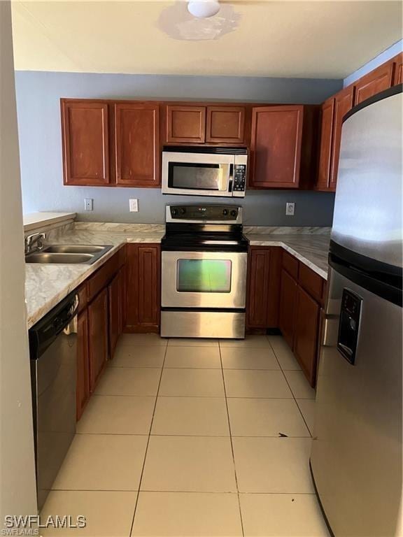 kitchen featuring light tile patterned floors, appliances with stainless steel finishes, light countertops, and a sink