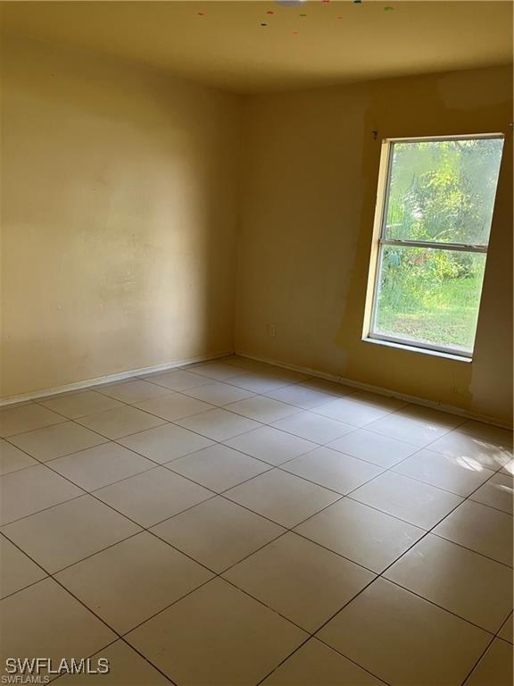 empty room with light tile patterned floors and baseboards