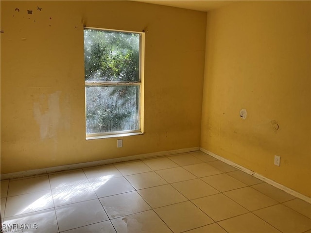 tiled empty room featuring a wealth of natural light and baseboards