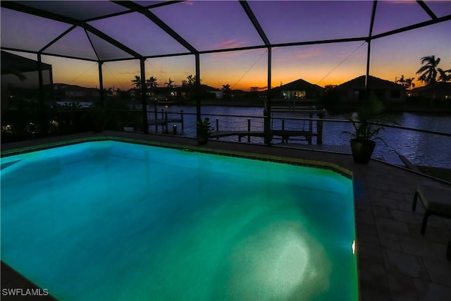 pool at dusk with glass enclosure, a water view, and an outdoor pool