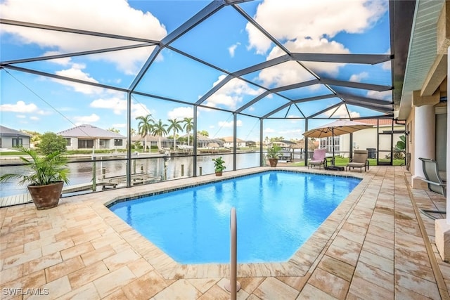 outdoor pool with a water view, glass enclosure, and a patio