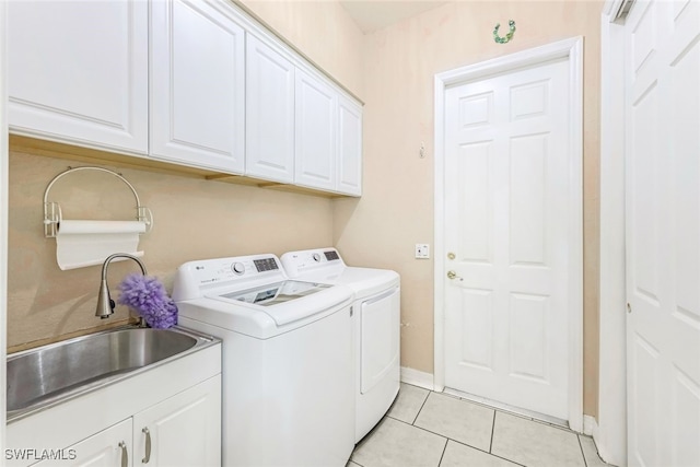 laundry area with light tile patterned floors, a sink, baseboards, cabinet space, and washer and clothes dryer