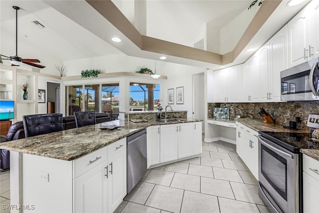 kitchen featuring a sink, visible vents, open floor plan, appliances with stainless steel finishes, and dark stone counters