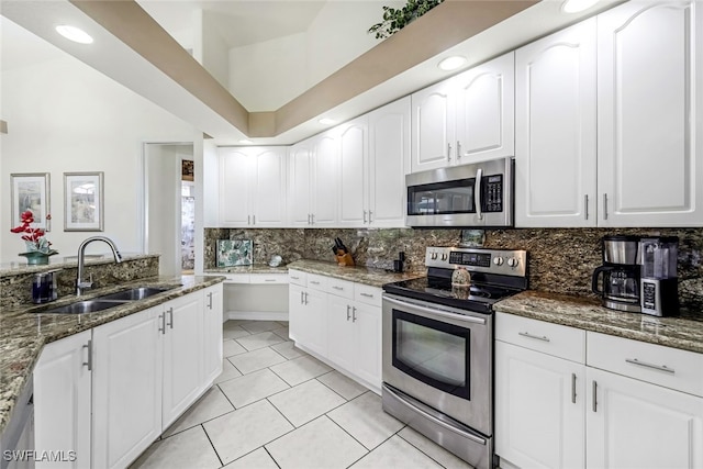 kitchen with light tile patterned floors, a sink, appliances with stainless steel finishes, dark stone counters, and tasteful backsplash