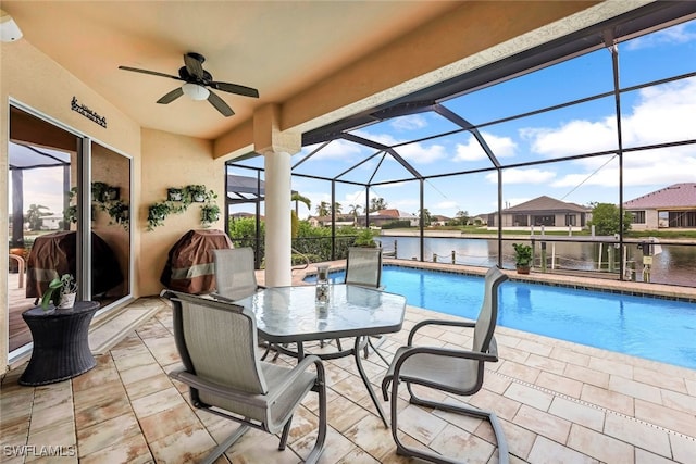 pool with a ceiling fan, glass enclosure, a patio area, and a water view