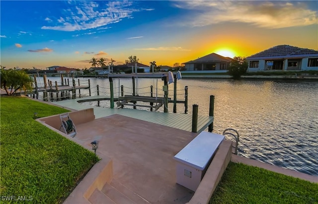 dock area with a water view, a lawn, and boat lift