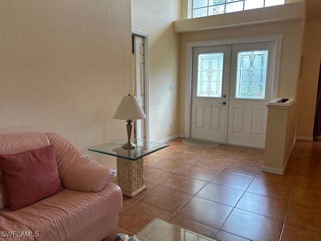 entryway with french doors, a towering ceiling, baseboards, and light tile patterned floors