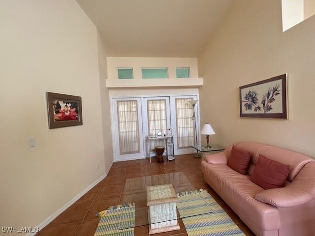 tiled living area with a towering ceiling and baseboards