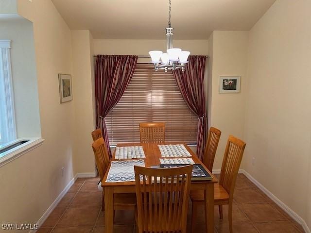 dining space with tile patterned flooring, baseboards, and an inviting chandelier