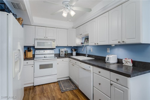 kitchen featuring dark wood-style floors, dark countertops, visible vents, a sink, and white appliances