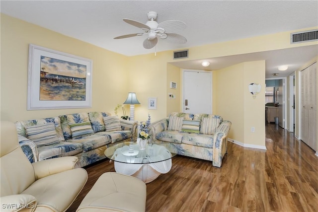 living room featuring baseboards, visible vents, ceiling fan, and wood finished floors