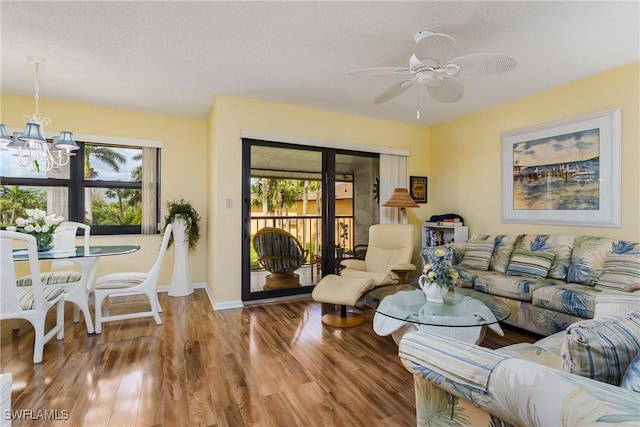 living area featuring plenty of natural light, baseboards, wood finished floors, and ceiling fan with notable chandelier