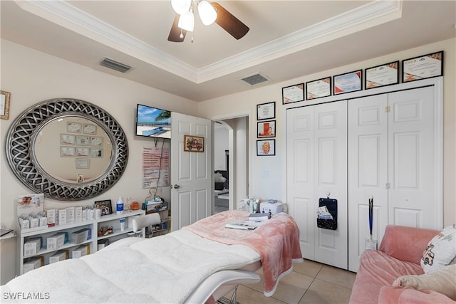 bedroom with light tile patterned floors, visible vents, a raised ceiling, and ornamental molding