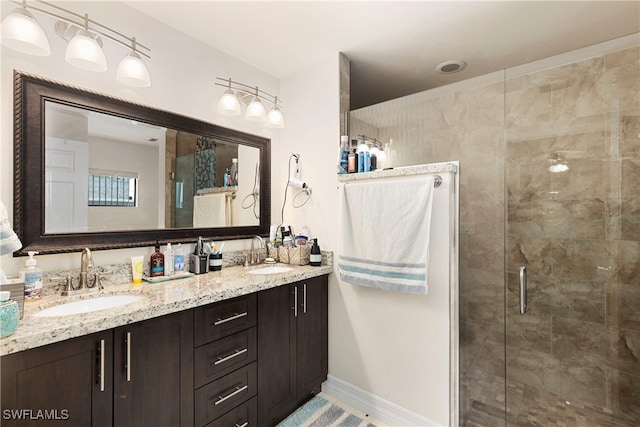 full bathroom with a stall shower, a sink, baseboards, and double vanity