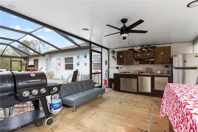 living room featuring light wood-style floors, ceiling fan, and a sunroom