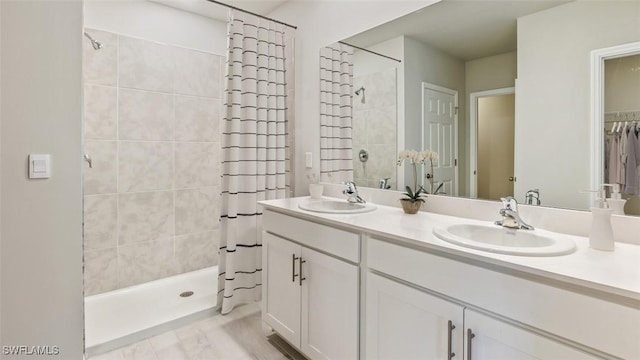 full bath with double vanity, a stall shower, and a sink