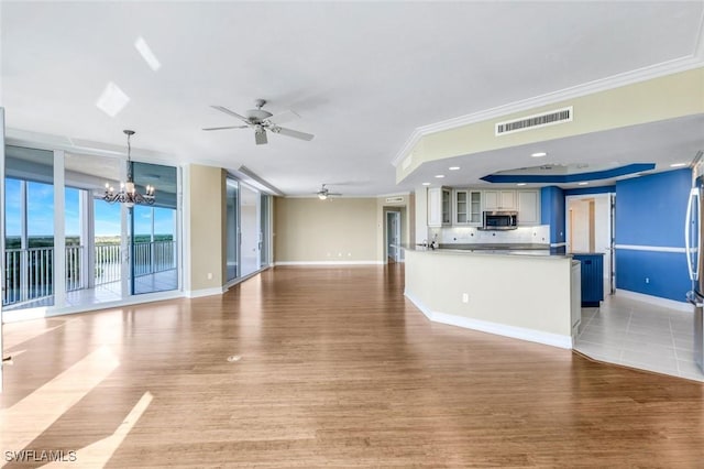 unfurnished living room with light wood-style flooring, ceiling fan with notable chandelier, visible vents, and ornamental molding