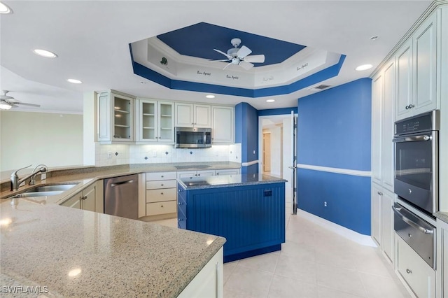 kitchen with a warming drawer, a sink, a tray ceiling, appliances with stainless steel finishes, and ceiling fan