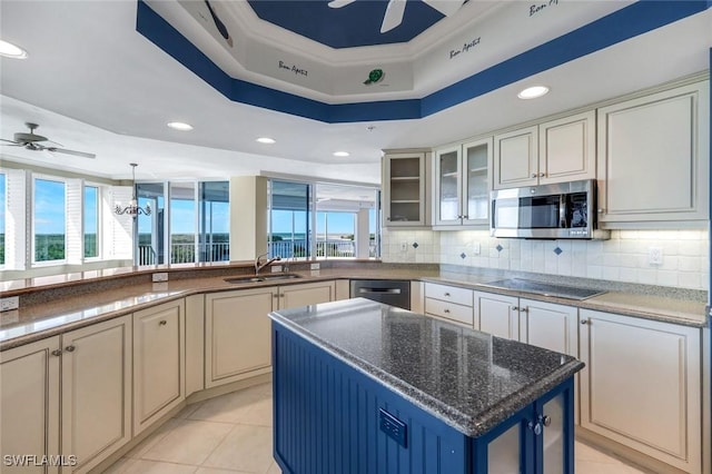 kitchen featuring a sink, a tray ceiling, ceiling fan with notable chandelier, and stainless steel appliances