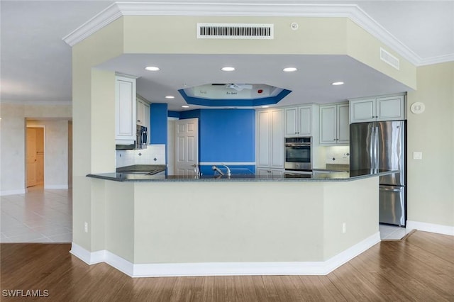 kitchen featuring stainless steel appliances, visible vents, wood finished floors, and crown molding