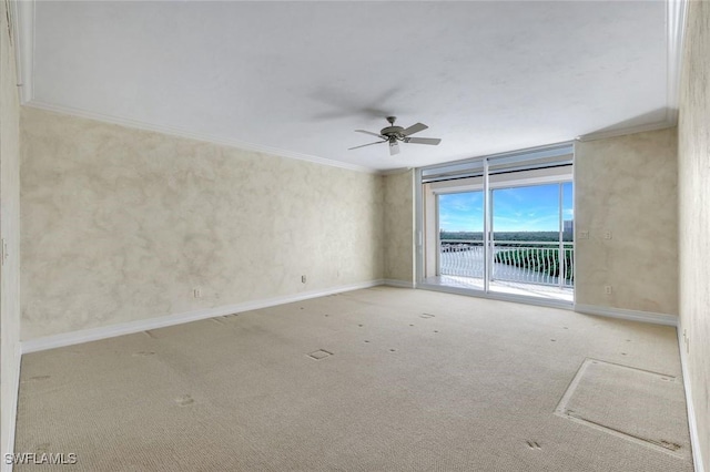 carpeted empty room with ceiling fan, baseboards, and ornamental molding