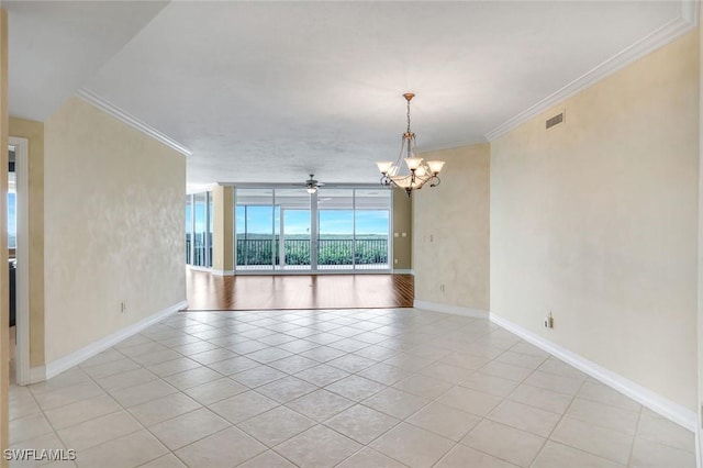 spare room featuring ceiling fan with notable chandelier, floor to ceiling windows, crown molding, light tile patterned floors, and baseboards