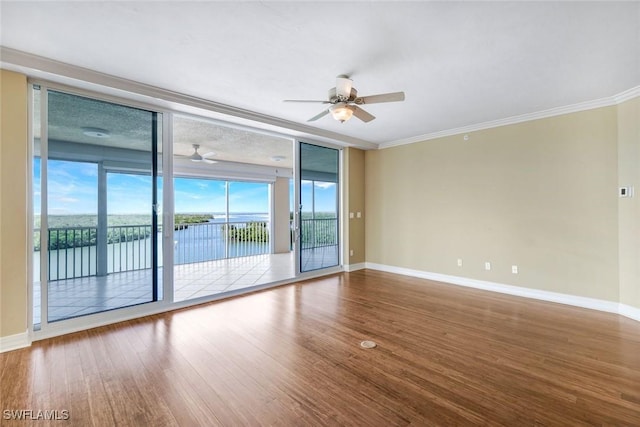 empty room featuring floor to ceiling windows, wood finished floors, baseboards, and ornamental molding