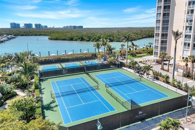 view of tennis court with fence and a water view