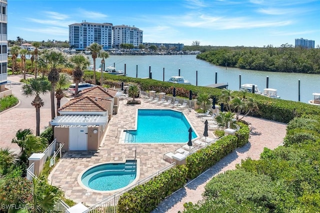 community pool with a water view, fence, and a patio area