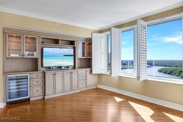 interior space with crown molding, wine cooler, wood finished floors, and baseboards