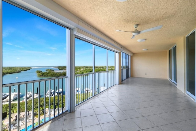 unfurnished sunroom featuring a ceiling fan and a water view