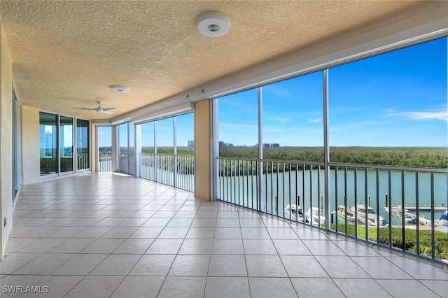 unfurnished sunroom featuring a ceiling fan and a water view